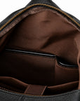 Black full-grain leather backpack interior with brown fabric lining and leather-trimmed organizer pockets