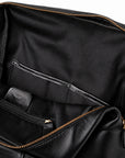 Close-up of the interior of a black leather bag, showing a spacious black fabric lining, a zippered pocket, and gold-tone zipper hardware.