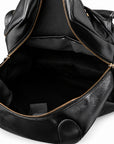 Black leather bag shown open to display the interior, featuring a black fabric lining and gold-tone zippers.