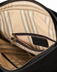 Close-up of the interior of a black bag, showing a beige and brown striped lining with a zippered pocket and gold-tone zipper hardware.