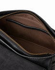 Close-up of the interior of a black leather bag, showing a brown fabric lining with a zippered compartment and gold-tone zipper teeth.