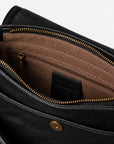 Close-up of the interior of a black leather bag, showing a brown fabric-lined compartment with gold-tone zippers and hardware.