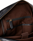 Close-up of the interior of a black leather bag showing a brown fabric lining with a zippered pocket and gold-tone zipper hardware.