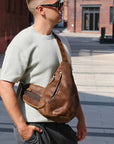 Man wearing a brown leather bag on a city street