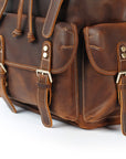 Close-up of a brown leather backpack with gold buckles on a white background