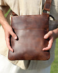 Man holding a brown Crazy Horse leather crossbody bag, showcasing its premium quality and versatile design.