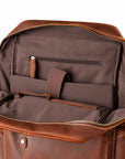 Open brown leather briefcase or duffel bag showing the interior organization with a dark brown fabric lining, zip pocket, elastic strap, and storage compartments.