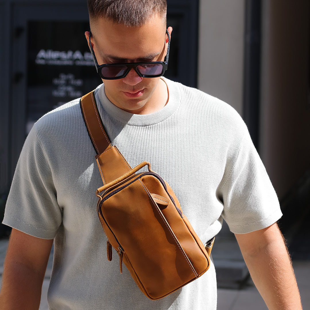 brown leather sling crossbody bag worn by man in street style outfit, compact everyday carry bag