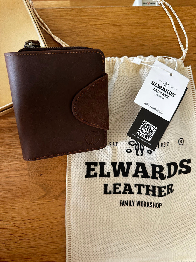 Brown leather wallet in soft pouch, with brand tag and premium finish, ready for gifting.