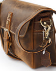 Brown leather satchel bag with gold accents on a white background
