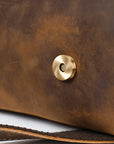 Close-up of a brown leather surface with a gold button