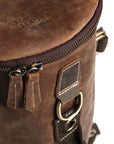 Close-up of the top section of a handcrafted leather backpack, showing stitching, sturdy zippers, and durability for travel.