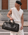Durable black leather weekender bag for men with dual carry handles, zip closure and large overnight travel capacity