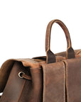 Close-up of the top handle and back straps of a vintage brown Crazy Horse leather backpack, highlighting stitching.