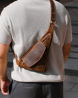 Person wearing a brown leather crossbody bag on a stone pavement