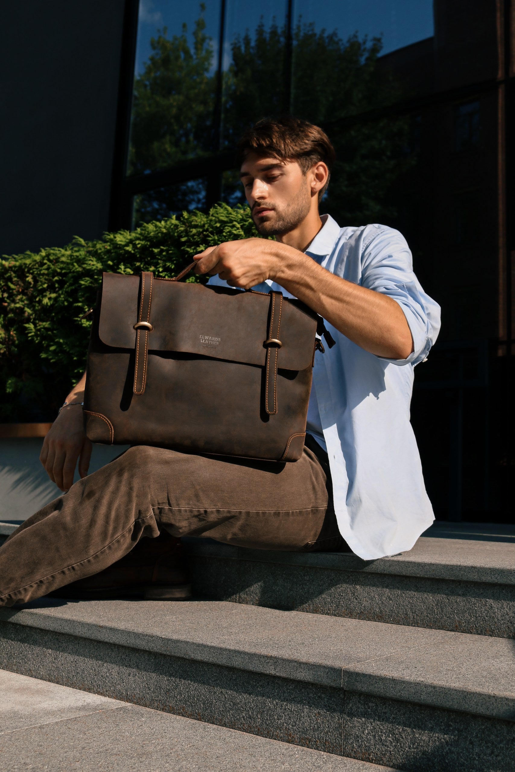 Man holding a brown leather briefcase outdoors