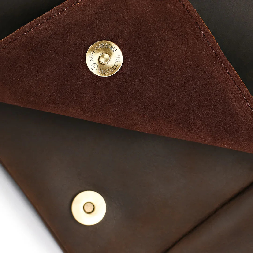 Magnetic snap closure and suede lining details on a men's brown leather satchel bag, showcasing quality craftsmanship.