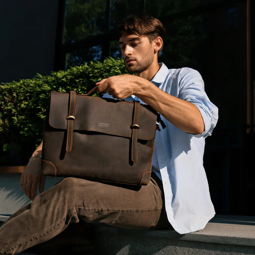A man in casual attire holding a vintage leather messenger bag, emphasizing its versatility and stylish design.