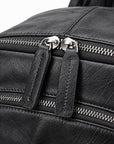 Close-up of a black textured leather bag with dual silver-tone zippers and pull tabs on a white background.