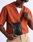 Close-up of a black leather crossbody bag with an adjustable shoulder strap