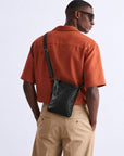 Back view of a man wearing a black leather crossbody bag over the shoulder