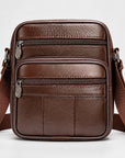 A brown leather crossbody bag with multiple zippered compartments and a wide adjustable shoulder strap, shown against a plain light gray background.