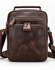 A dark brown distressed leather crossbody bag with a top handle, front zippered pocket, and adjustable shoulder strap, shown on a clean white background.