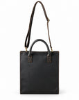 Minimalist black full-grain leather tote with an adjustable shoulder strap and metal clips