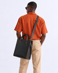 Modern black leather business tote for men with structured tall design, top handles, contrast stitching and detachable shoulder strap