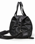 Modern black full-grain leather duffel bag side view with a rounded zip pocket and metal clips.