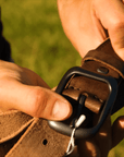 Unboxing a handcrafted brown leather belt, highlighting the vintage buckle, smooth texture, and branded pouch packaging.