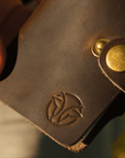Unboxing a handcrafted leather card holder, showcasing premium packaging, embossed logo, button clasp, and card slots.