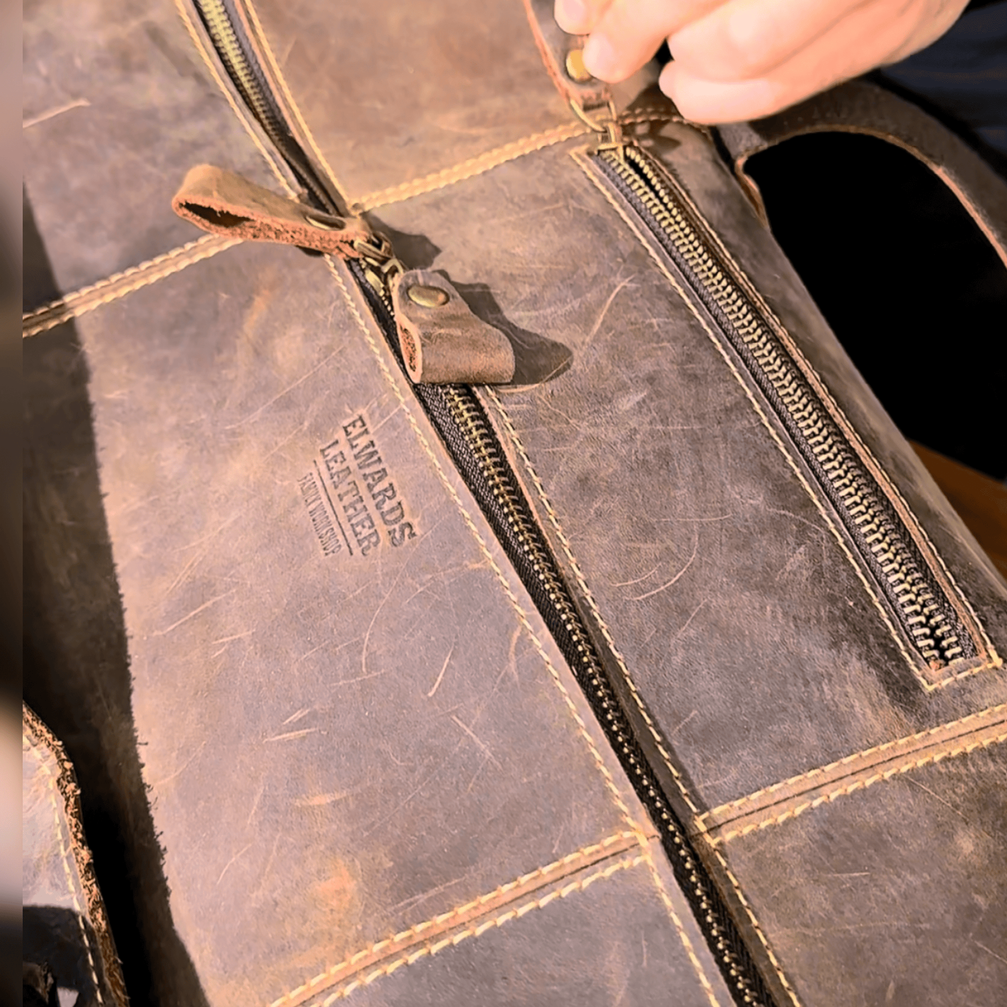 Vintage leather duffle bag on a table, featuring brass zippers, spacious compartments, and handcrafted Crazy Horse leather.