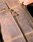 Vintage leather duffle bag on a table, featuring brass zippers, spacious compartments, and handcrafted Crazy Horse leather.