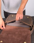 Demonstration of a dark brown leather satchel showing durable zippers, compartments, adjustable strap, and overall design