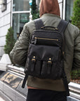 Professional black leather backpack for men with multiple front pockets, gold-tone zippers and padded straps for business and travel