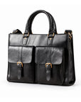 A black leather briefcase with twin buckle flap pockets and rounded handles is shown in a front three-quarter view.
