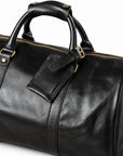 Refined black full-grain leather duffel bag with a buckled leather luggage tag