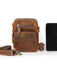 Brown leather crossbody bag with a smartphone on a white background