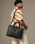 Structured black leather business bag for men with dual carry handles, contrast stitching and adjustable shoulder strap
