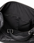 Textured black full-grain leather weekender bag interior with two leather-trimmed slip pockets