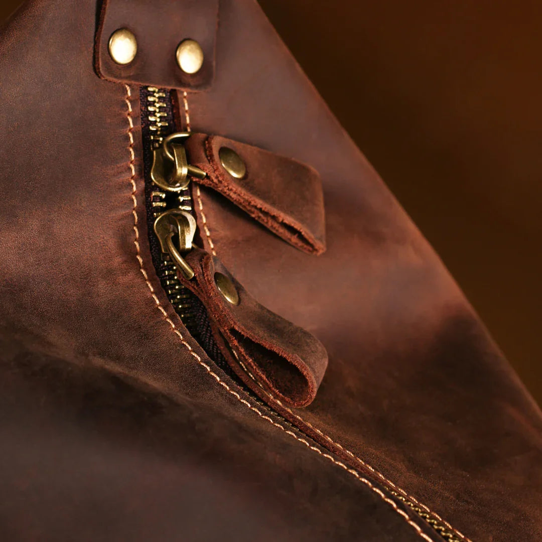 Close-up of high-quality brass zipper pull and stitching on vintage handmade leather travel duffle bag