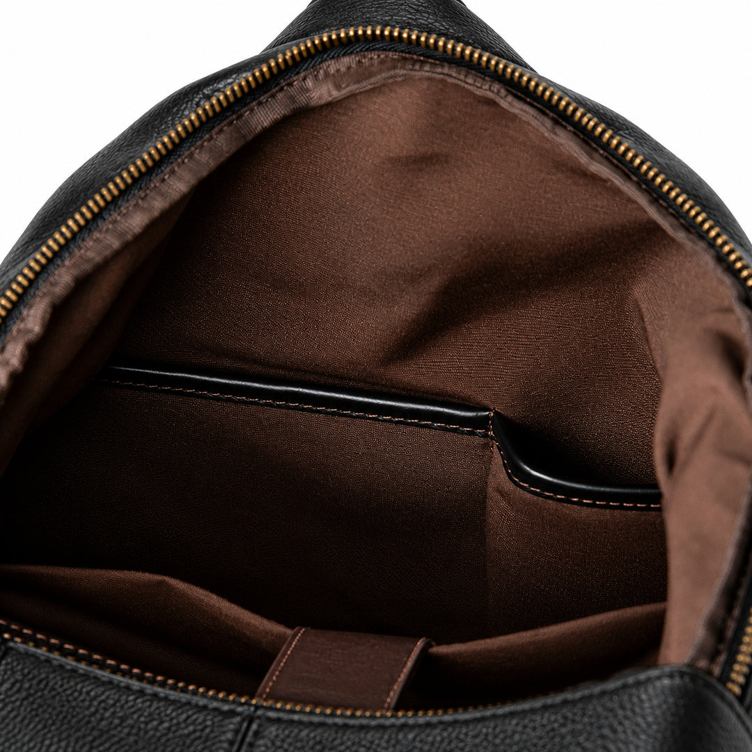 Black full-grain leather backpack interior with brown fabric lining and leather-trimmed organizer pockets