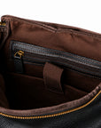 Black full-grain leather backpack interior with brown lining and a leather-trimmed zipper pocket