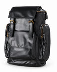 Black full-grain leather backpack with twin buckles and side zip pockets, three-quarter view