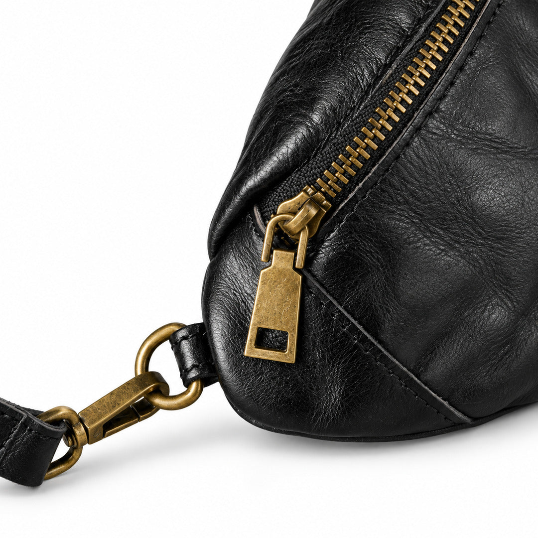 Close-up of a black leather bag with a gold-tone zipper pull and matching hardware.