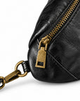 Close-up of a black leather bag with a gold-tone zipper pull and matching hardware.
