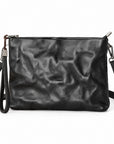 Black leather clutch bag with a crinkled texture, featuring a wristlet strap, top zipper closure, and a detachable shoulder strap.