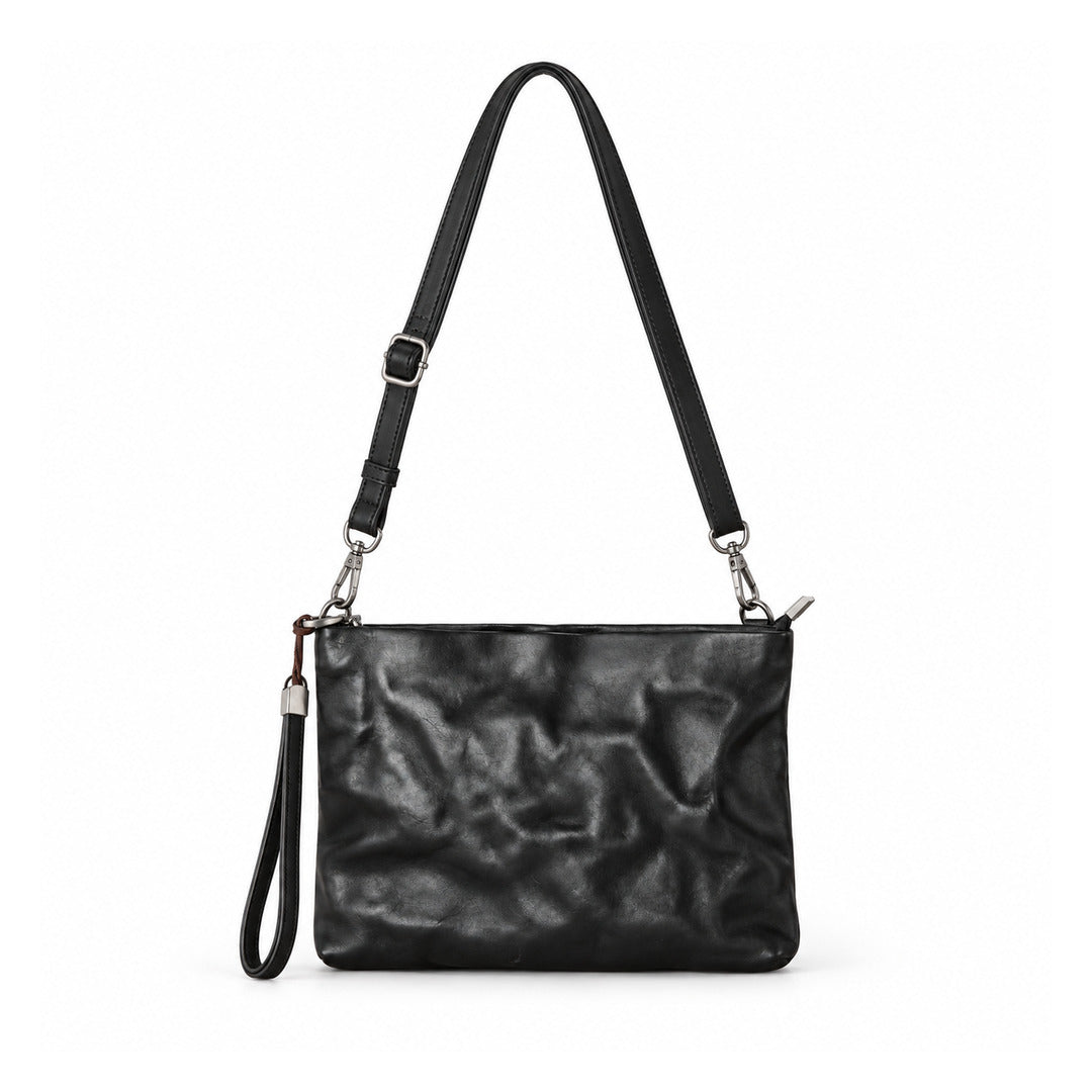 A black textured leather shoulder bag with a crinkled finish, featuring a long adjustable shoulder strap, a wristlet strap, and silver-tone hardware.
