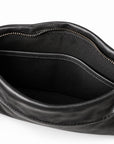 Close-up of the interior of a black leather handbag, showing a zippered opening, black fabric lining, and silver-tone metal hardware.